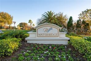 A stone monument sign for the Water Ridge community stands amidst landscaped greenery and trees — 402 WATERFERN TRAIL DRIVE, AUBURNDALE, FL