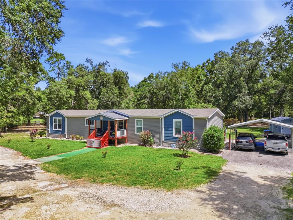 A single-story manufactured home with a red porch and a detached metal carport — 12185 198TH TERRACE, O'BRIEN, FL