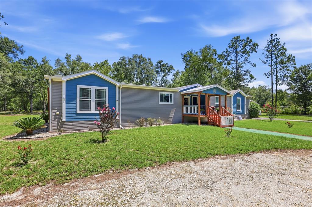 A single-story modular home with blue and gray siding features a front porch and lawn — 12185 198TH TERRACE, O'BRIEN, FL