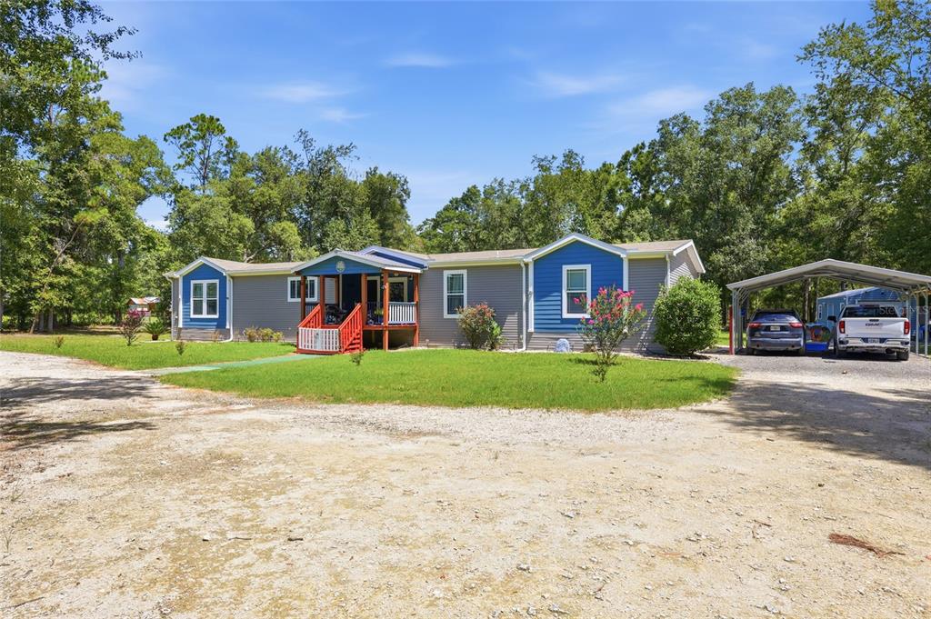 A single-story house with gray and blue siding features a front porch and carport — 12185 198TH TERRACE, O'BRIEN, FL