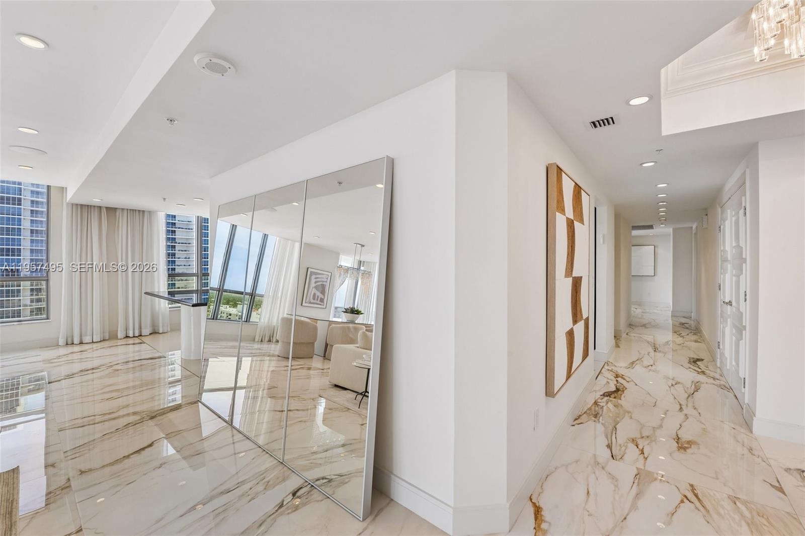 A hallway with marble floors and a large mirror leads to a bright living area — 3535 S Ocean Dr # 2106, Hollywood FL 33019, HOLLYWOOD, FL