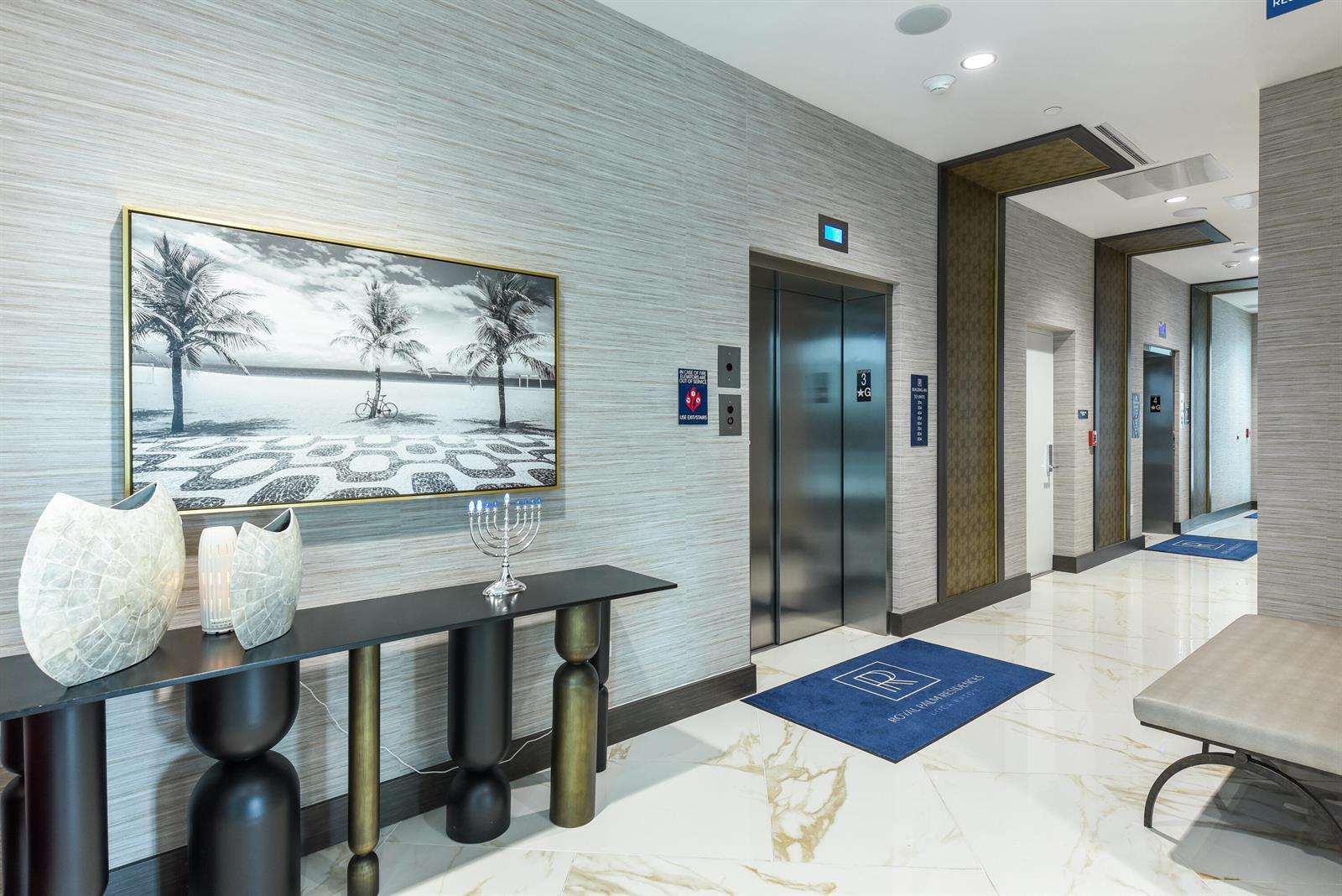 A modern elevator lobby features textured wallpaper, a console table, artwork, and marble flooring — 485 E Royal Palm Road # 403, Boca Raton FL 33432, BOCA RATON, FL