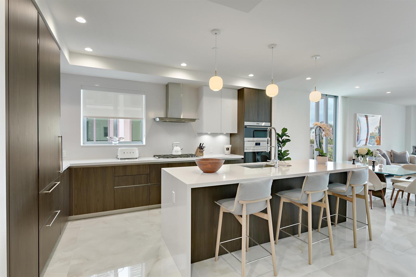 A modern kitchen features dark wood cabinetry, white countertops, a large island, and three pendant lights — 485 E Royal Palm Road # 403, Boca Raton FL 33432, BOCA RATON, FL
