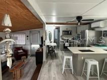 A kitchen island with gray cabinets sits in front of a bedroom with a bed — 3717 115TH STREET COURT W, BRADENTON, FL