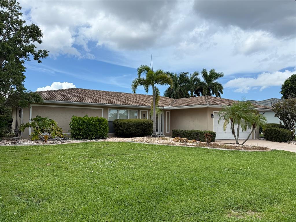 A single-story house with a tan exterior, a tiled roof, and a front lawn — 821 VIA TUNIS, PUNTA GORDA, FL