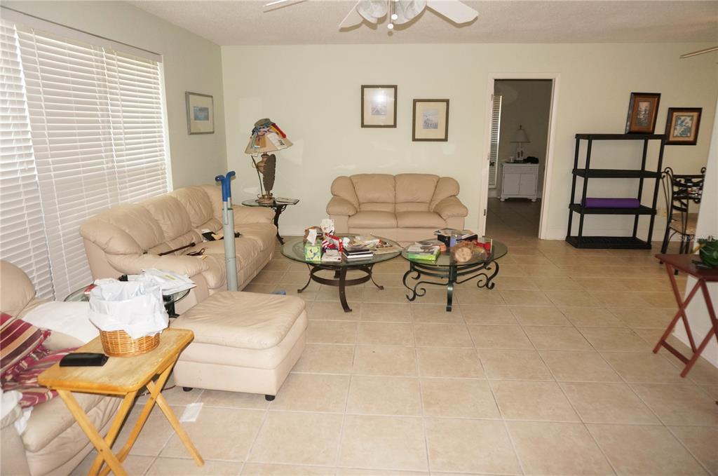 A living room with beige sofas, two glass coffee tables, and light-colored tile flooring — 821 VIA TUNIS, PUNTA GORDA, FL