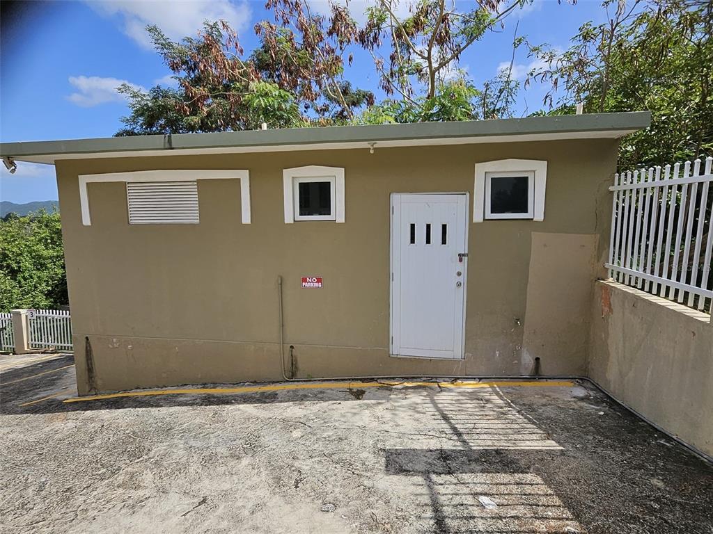 A tan exterior wall of a building features a white door, two windows, and signage — Km 5.8 CARR 311, CABO ROJO, PR