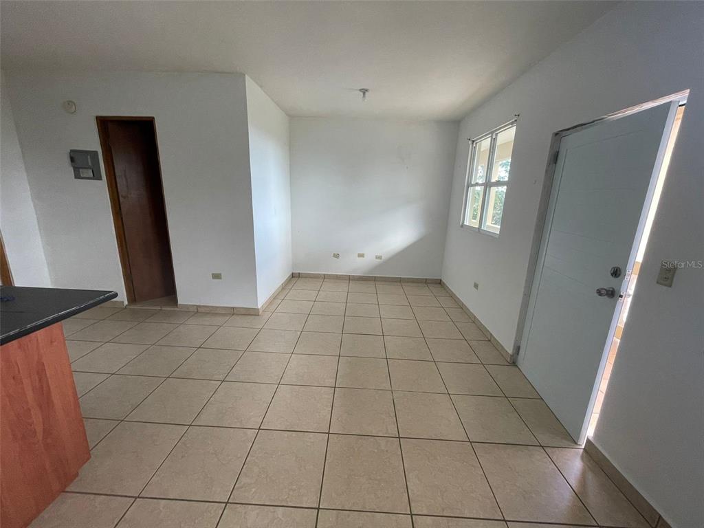 An empty room with beige tile flooring, white walls, a window, and a white door — Km 5.8 CARR 311, CABO ROJO, PR