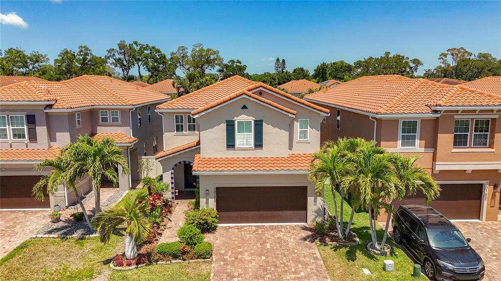 An exterior view of a two-story suburban house with a tiled roof and garage — 10193 GRAND OAK CIRCLE, MADEIRA BEACH, FL