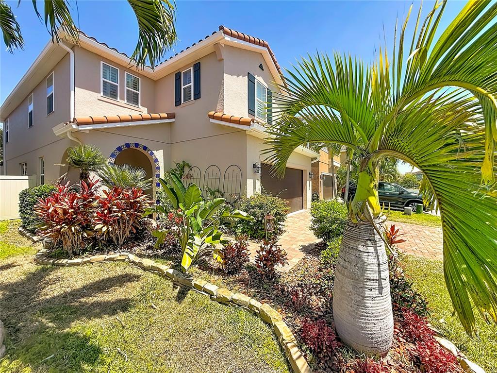 A two-story stucco house with a tile roof, arched entryway, and landscaped front yard — 10193 GRAND OAK CIRCLE, MADEIRA BEACH, FL