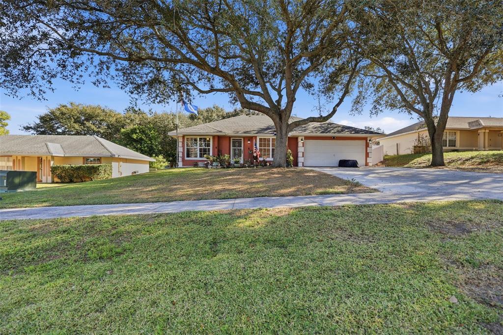 A single-story house with a white garage door and large trees in the front yard — 4254 WORTHINGTON PLACE, MASCOTTE, FL