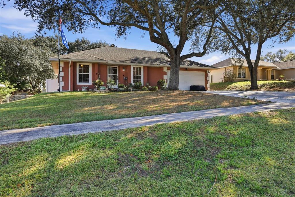 A single-story house with a red exterior, white trim, and a two-car garage — 4254 WORTHINGTON PLACE, MASCOTTE, FL