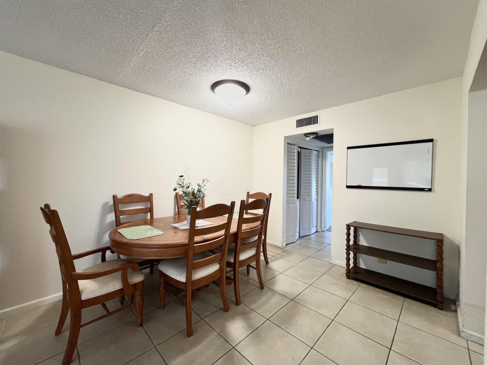 A dining room with a wooden table, chairs, tiled floors, and a wall-mounted whiteboard — 4023 Berkshire B # 4023, Deerfield Beach FL 33442, DEERFIELD BEACH, FL