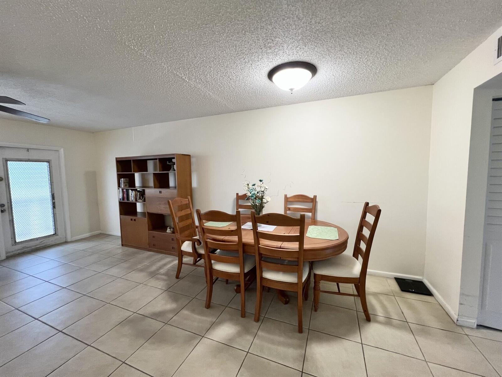 A dining room with tile flooring, a wooden table with six chairs, and a bookshelf — 4023 Berkshire B # 4023, Deerfield Beach FL 33442, DEERFIELD BEACH, FL