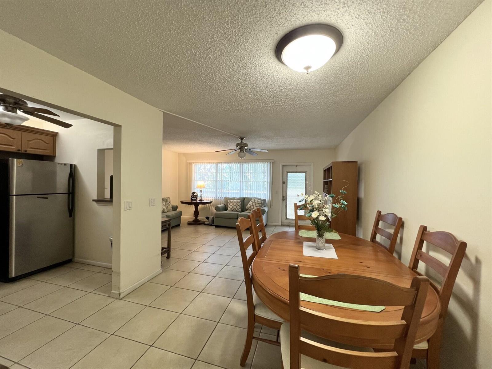 A dining area with a wooden table and chairs opens into a living room — 4023 Berkshire B # 4023, Deerfield Beach FL 33442, DEERFIELD BEACH, FL