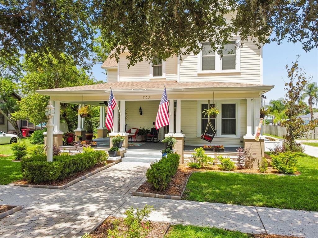 A two-story house with a covered front porch, American flags, and a brick walkway — 703 N EVERS STREET, PLANT CITY, FL