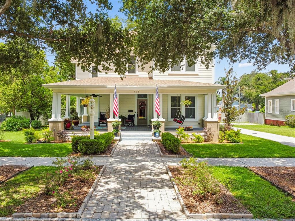 A two-story house with a covered front porch, American flags, and a brick walkway — 703 N EVERS STREET, PLANT CITY, FL