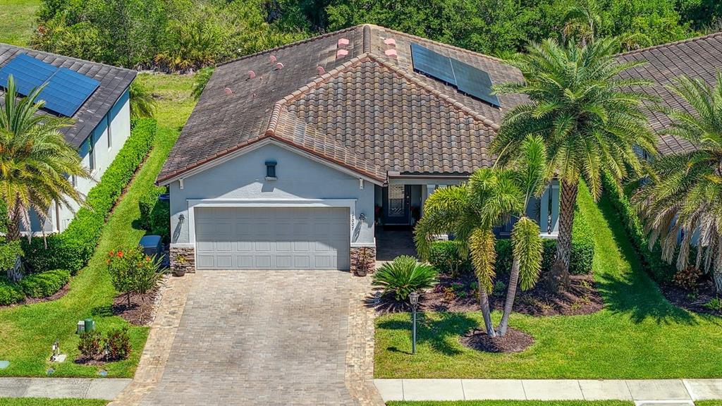 An aerial view of a single-story house with a tiled roof, solar panels, and driveway — 17007 BLUE RIDGE PLACE, BRADENTON, FL