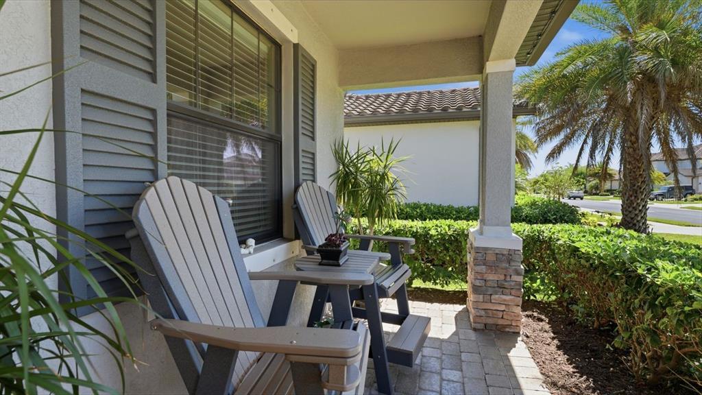 A covered front porch features two grey Adirondack chairs and a small table on pavers — 17007 BLUE RIDGE PLACE, BRADENTON, FL