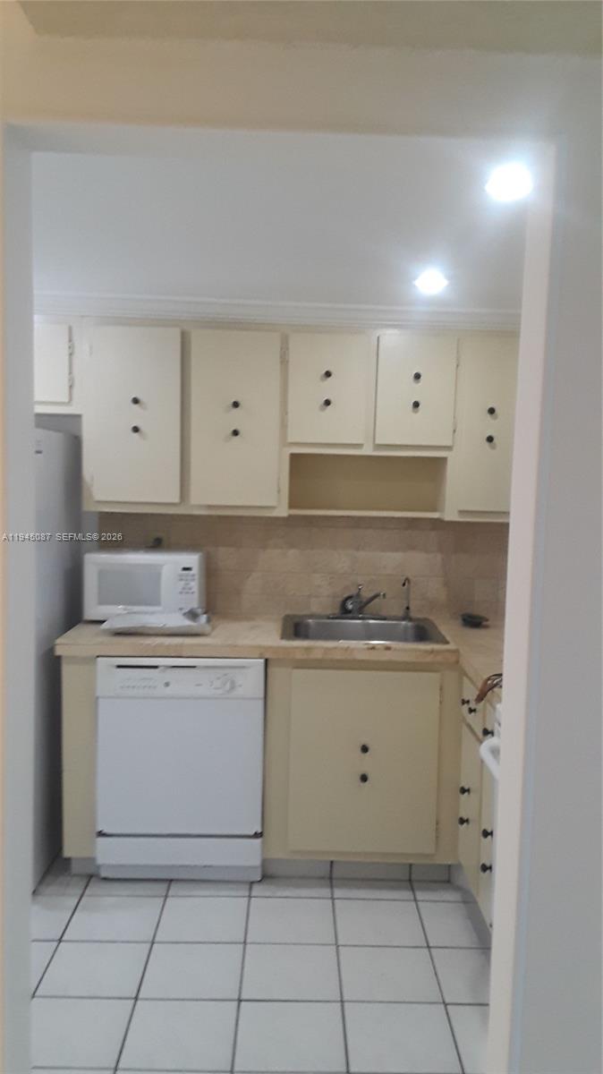 A small kitchen features light-colored cabinets, a white dishwasher, a microwave, and tiled flooring — 4374 NW 9th Ave # 3G, Deerfield Beach FL 33064, DEERFIELD BEACH, FL