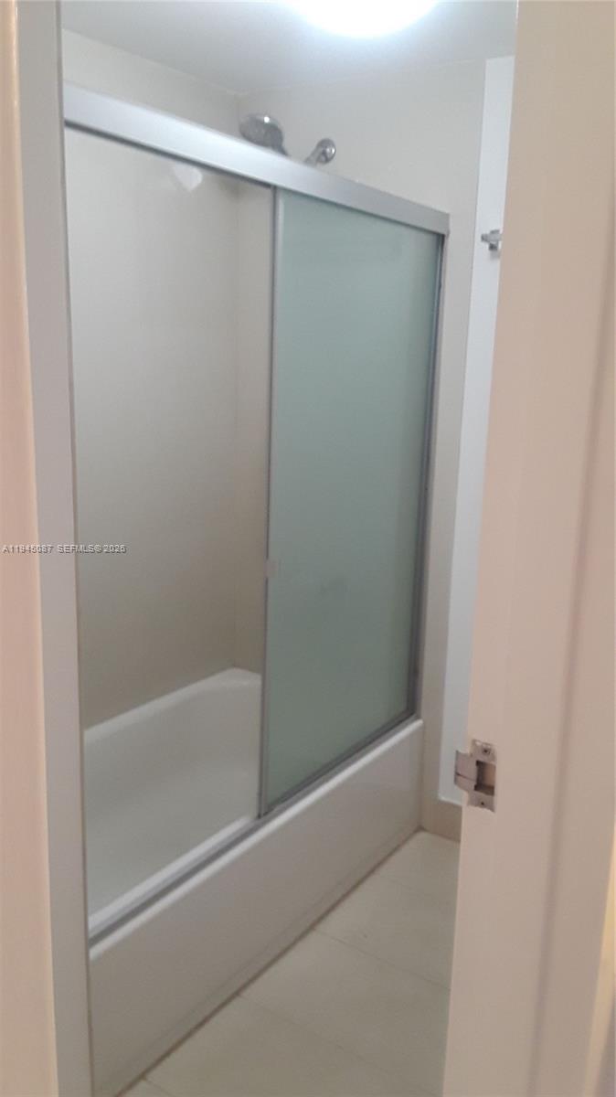 A bathroom features a white bathtub enclosed by a sliding glass door with frosted panels — 4374 NW 9th Ave # 3G, Deerfield Beach FL 33064, DEERFIELD BEACH, FL