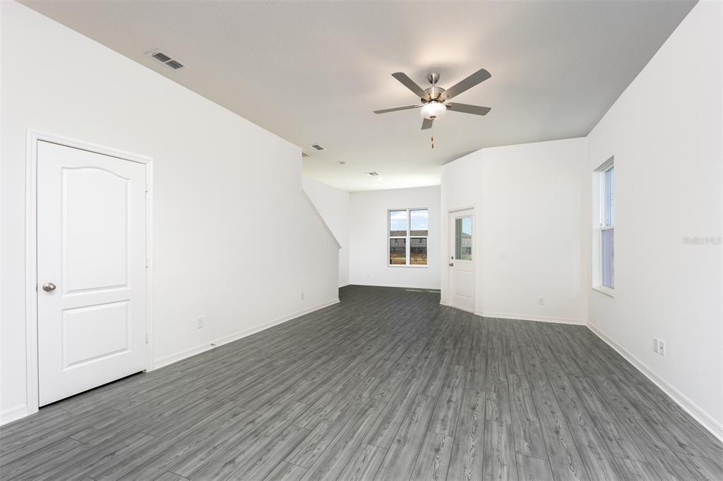 An empty room features white walls, gray wood-look flooring, a ceiling fan, and several windows — 648 POPPY LANE, DUNDEE, FL