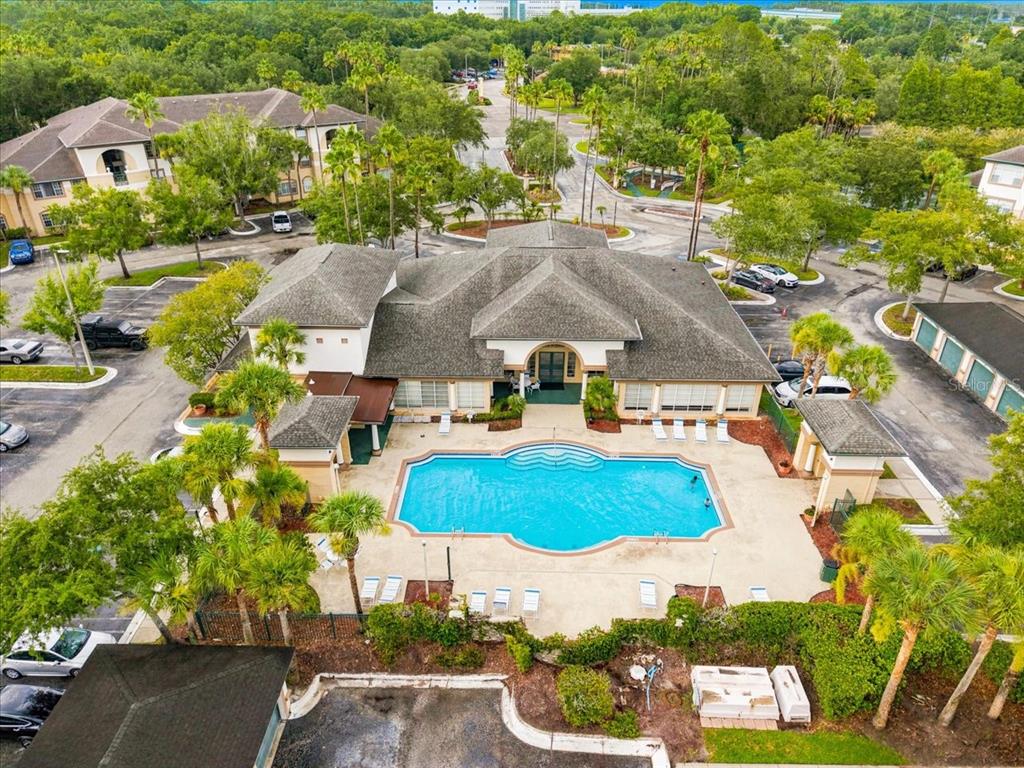 An aerial view shows a community clubhouse with a swimming pool surrounded by palm trees — 17104 CARRINGTON PARK DRIVE UNIT 516, TAMPA, FL