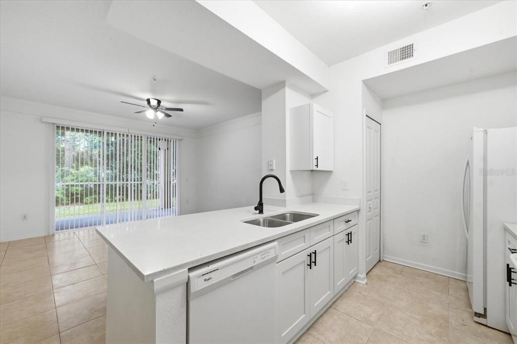 A kitchen with white cabinets, a quartz countertop, a black faucet, and tile flooring — 17104 CARRINGTON PARK DRIVE UNIT 516, TAMPA, FL