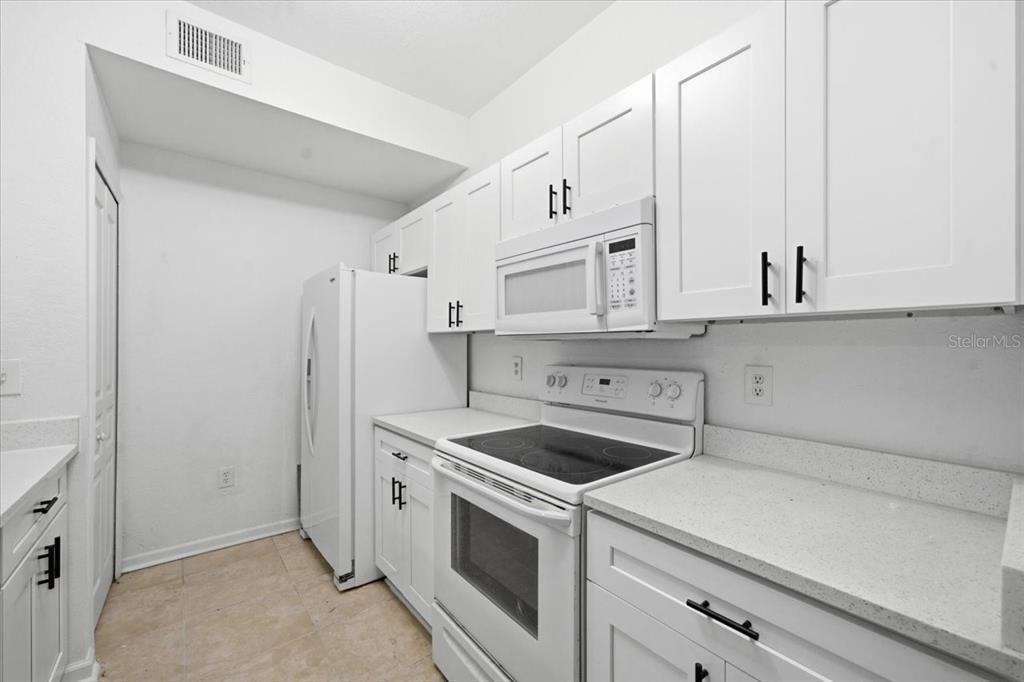 A kitchen features white cabinets, a white refrigerator, a white stove, and light-colored countertops — 17104 CARRINGTON PARK DRIVE UNIT 516, TAMPA, FL