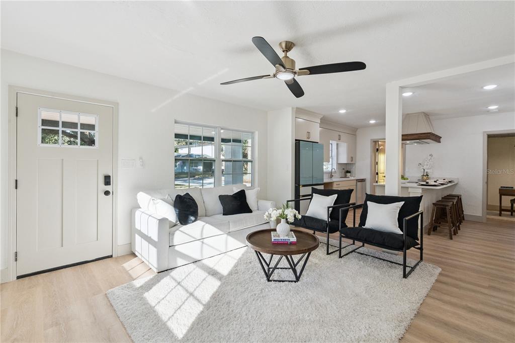 A living room with white walls, a white sofa, two black chairs, and a ceiling fan — 1931 CLOVERLAWN AVENUE, ORLANDO, FL