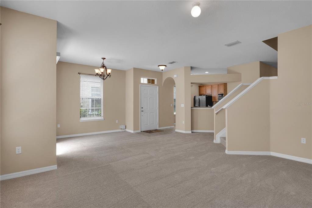 A carpeted living room features a front door, a dining area, and a staircase — 7001 INTERBAY BOULEVARD UNIT 119, TAMPA, FL