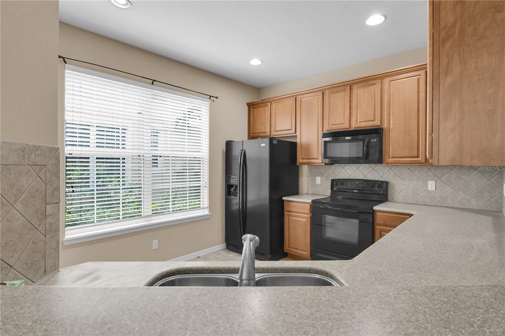 A kitchen features light wood cabinets, black appliances, a double sink, and a large window — 7001 INTERBAY BOULEVARD UNIT 119, TAMPA, FL