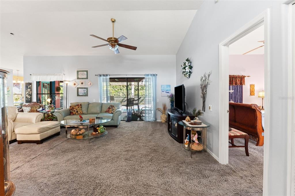 A living room with gray carpet, a ceiling fan, a sofa, and a television stand — 13732 TRIUMPH COURT, HUDSON, FL