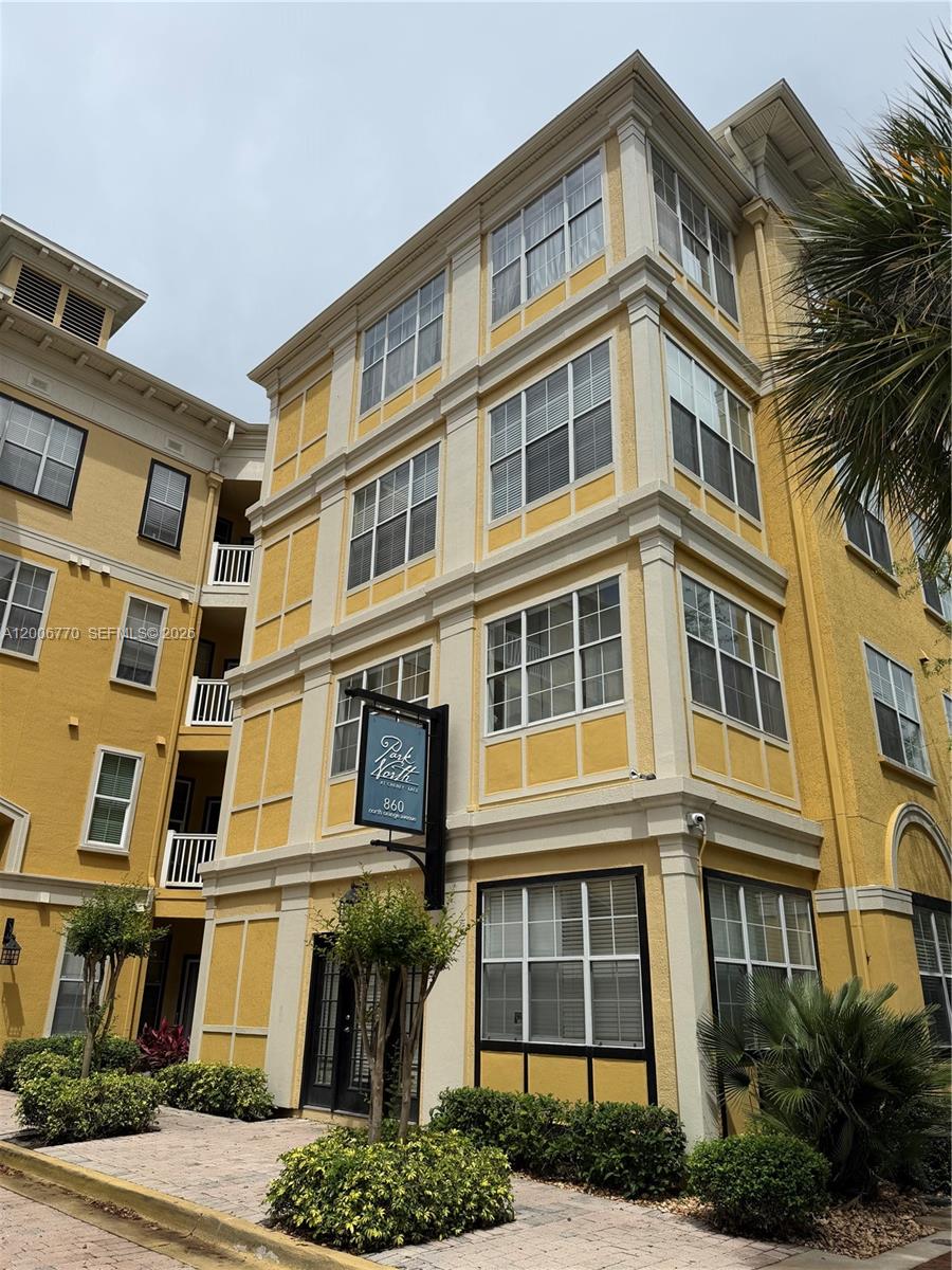 A four-story yellow apartment building with white trim and a black sign near the entrance — 860 N Orange Ave # 258, Orlando FL 33180, ORLANDO, FL