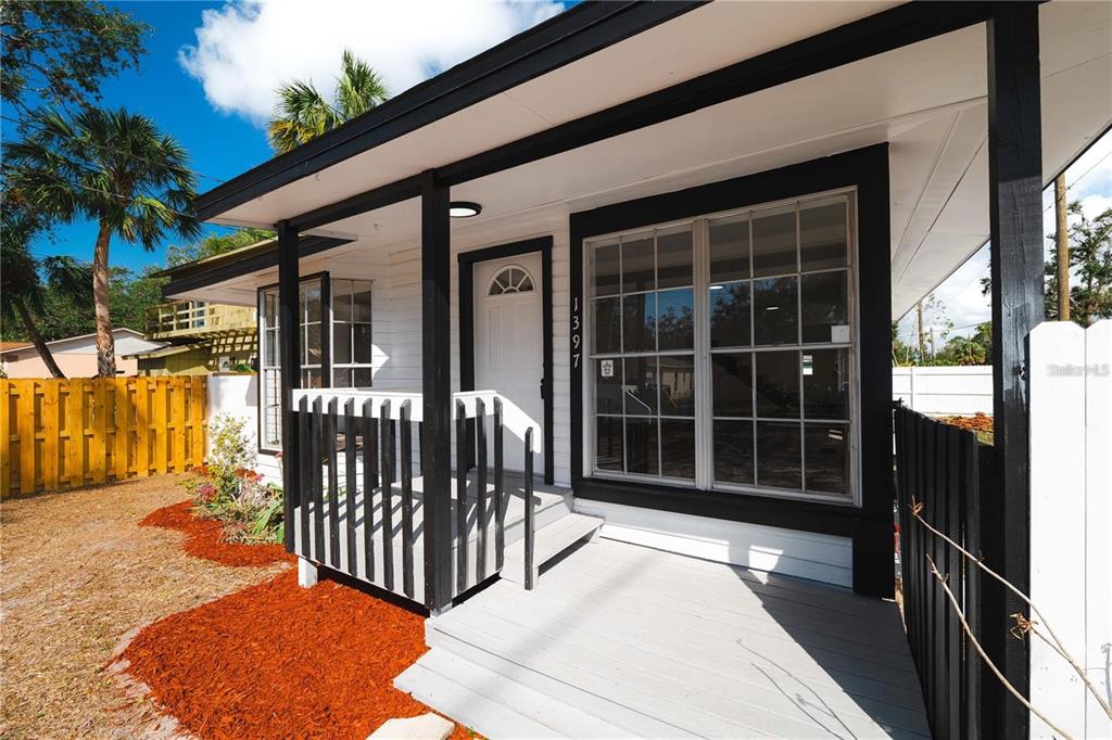 A white house exterior features a small front porch with black railings and trim — 1397 43RD STREET, SARASOTA, FL