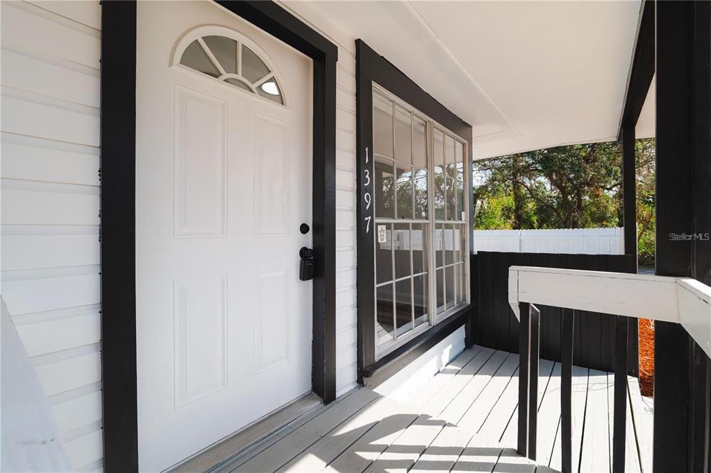 A white front door with a transom window sits beside a large window on a porch — 1397 43RD STREET, SARASOTA, FL