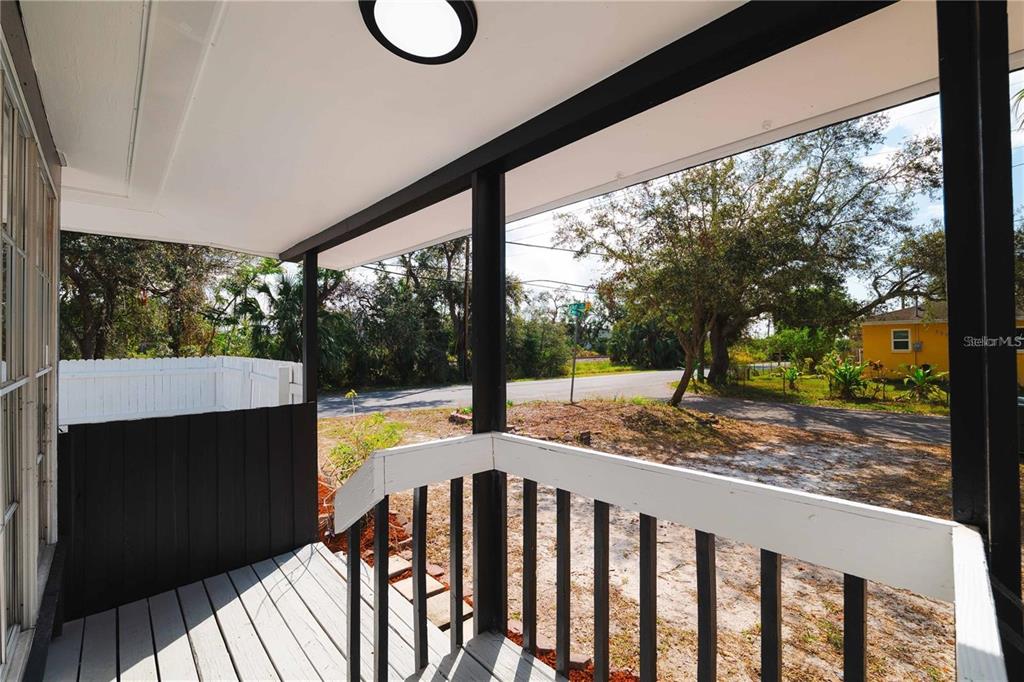A covered porch with a white wooden railing overlooks a street and trees — 1397 43RD STREET, SARASOTA, FL