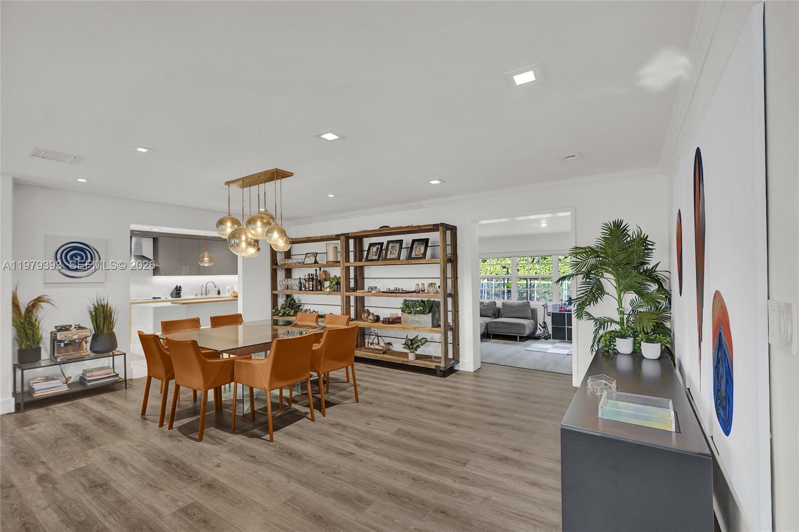 A dining room features a glass table, leather chairs, wood shelving, and light wood flooring — 2301 NE 196th St, Miami FL 33180, MIAMI, FL
