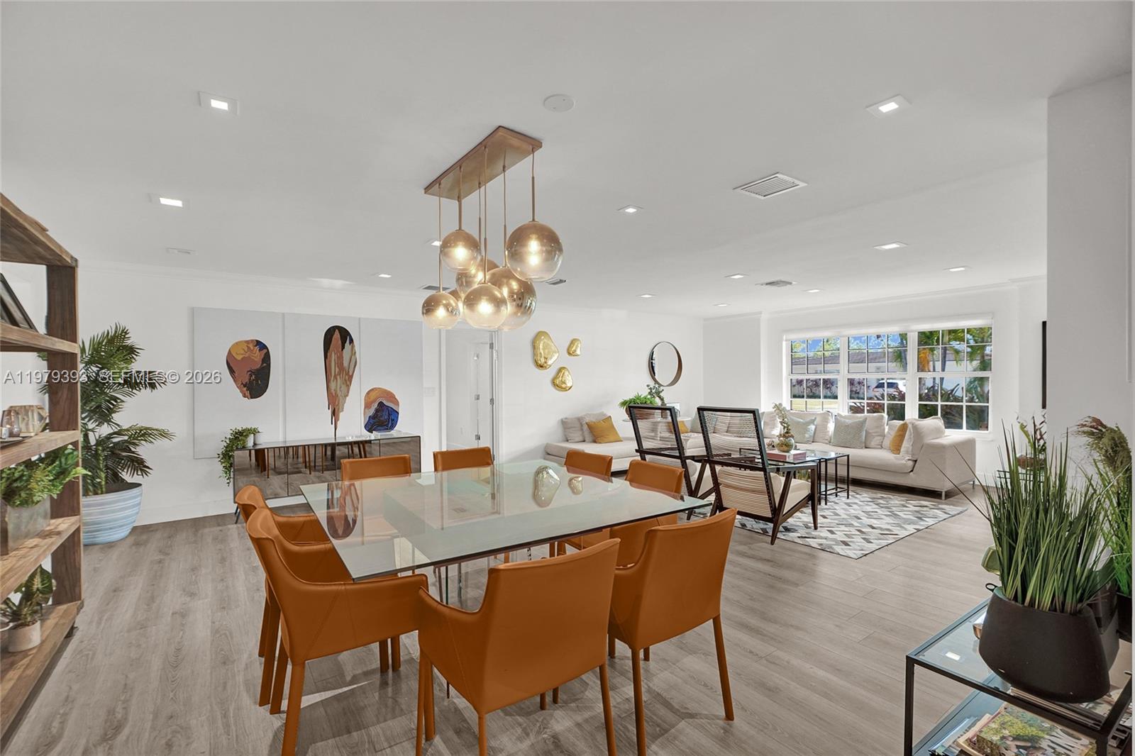 A dining area with a glass table and orange chairs opens into a living room — 2301 NE 196th St, Miami FL 33180, MIAMI, FL