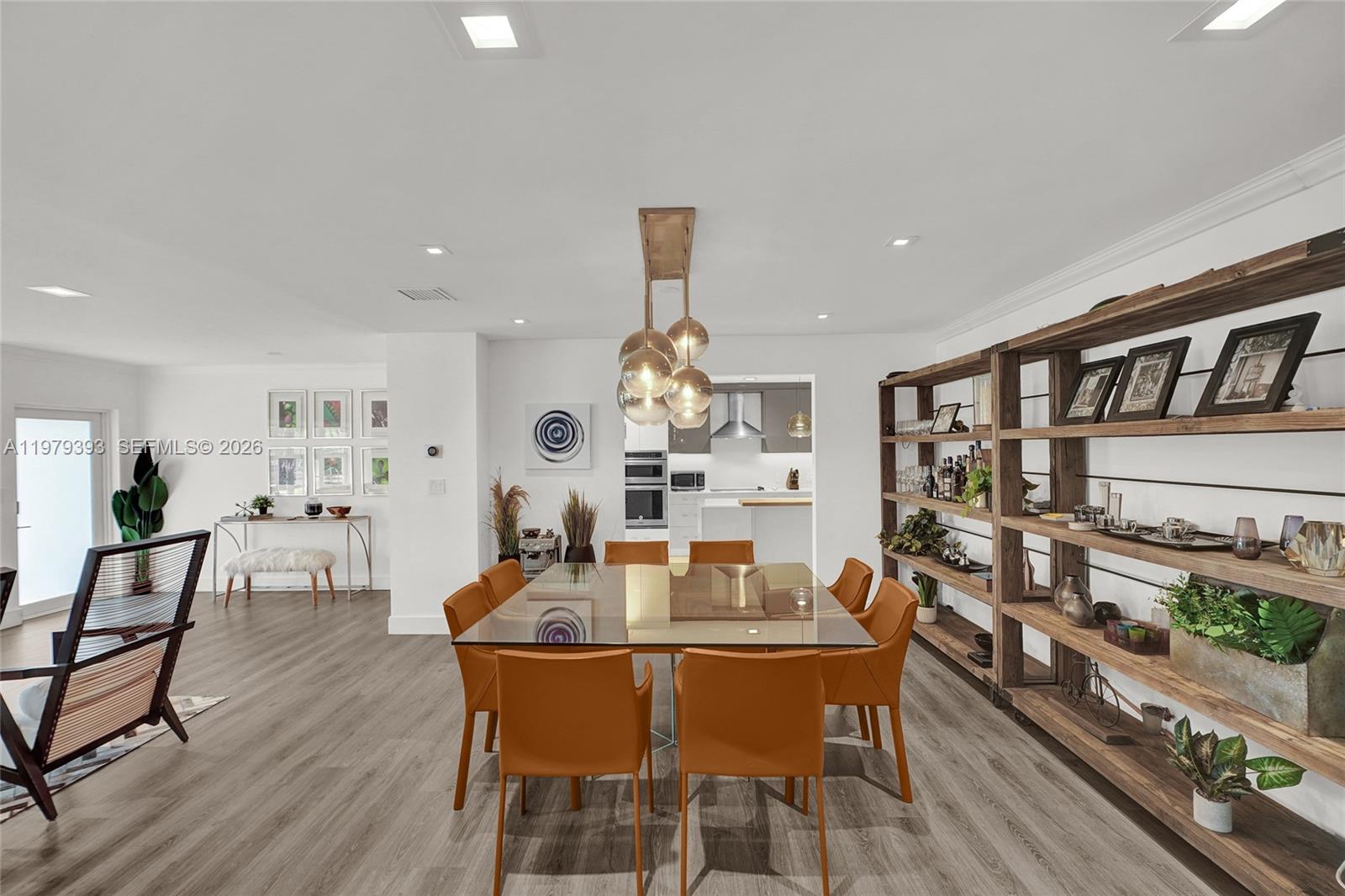 A dining room features a glass-topped table, orange chairs, and a large wooden shelving unit — 2301 NE 196th St, Miami FL 33180, MIAMI, FL