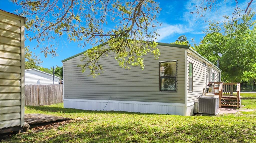 The exterior side of a light green manufactured home with a small wooden deck — 7429 W REVERE LANE, HOMOSASSA, FL