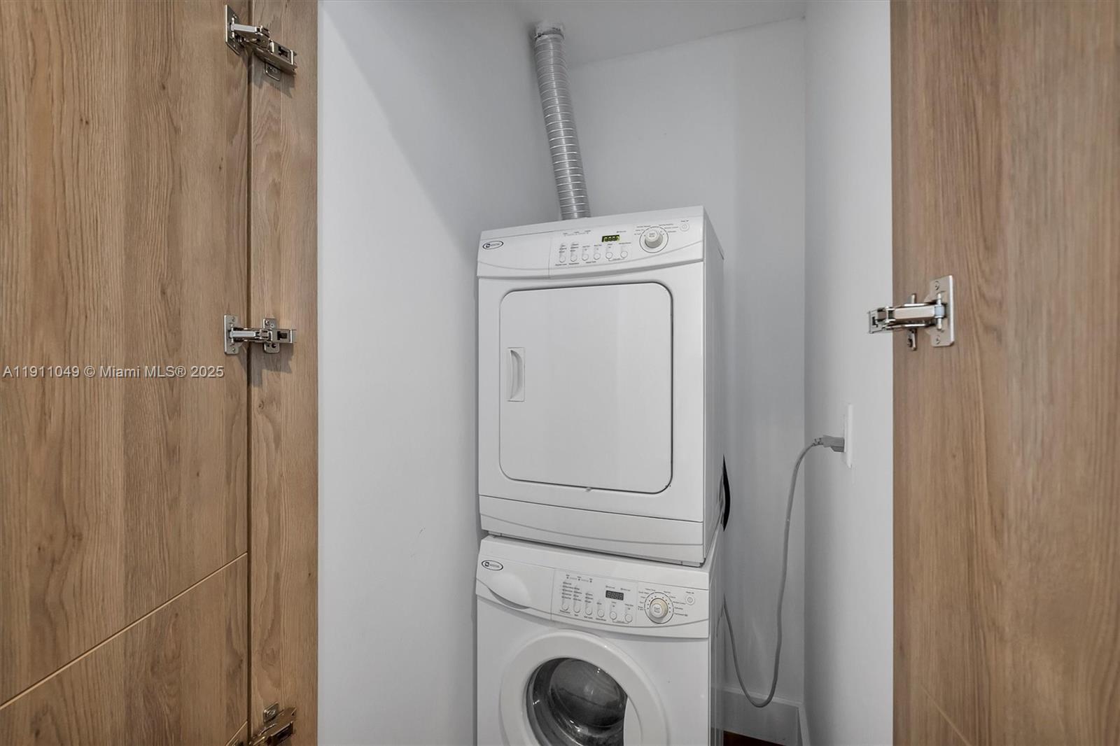 A stacked washer and dryer unit is installed inside a closet with wood-paneled doors — 3470 E Coast Ave, Miami FL 33137, MIAMI, FL
