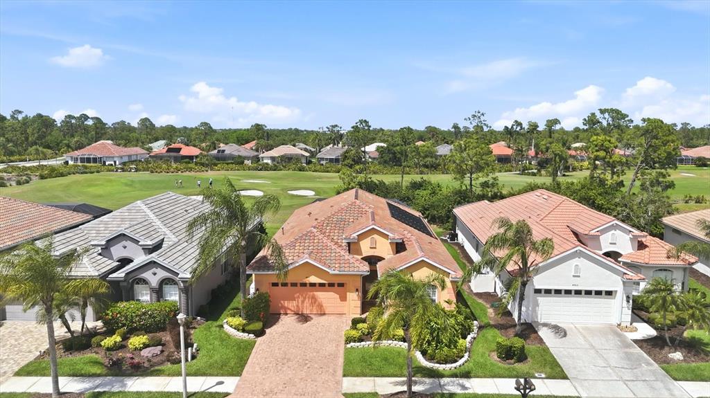 An aerial view shows three suburban houses with tiled roofs facing a golf course — 4811 BLUE HERON CIRCLE, NORTH PORT, FL
