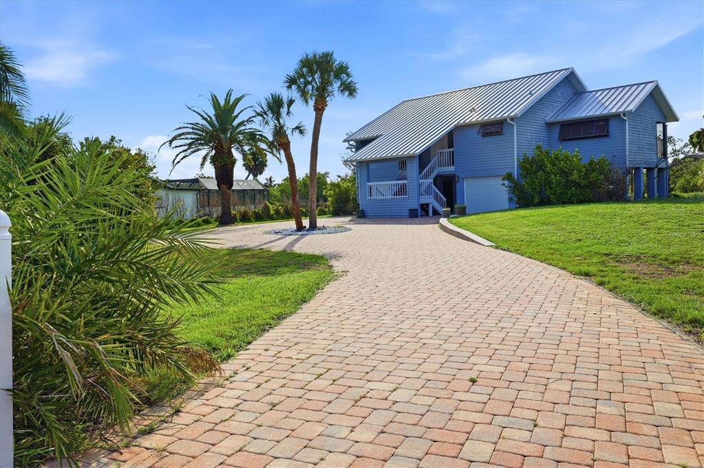 A blue two-story house with a metal roof and a paved driveway sits on grass — 1649 MANOR ROAD, ENGLEWOOD, FL