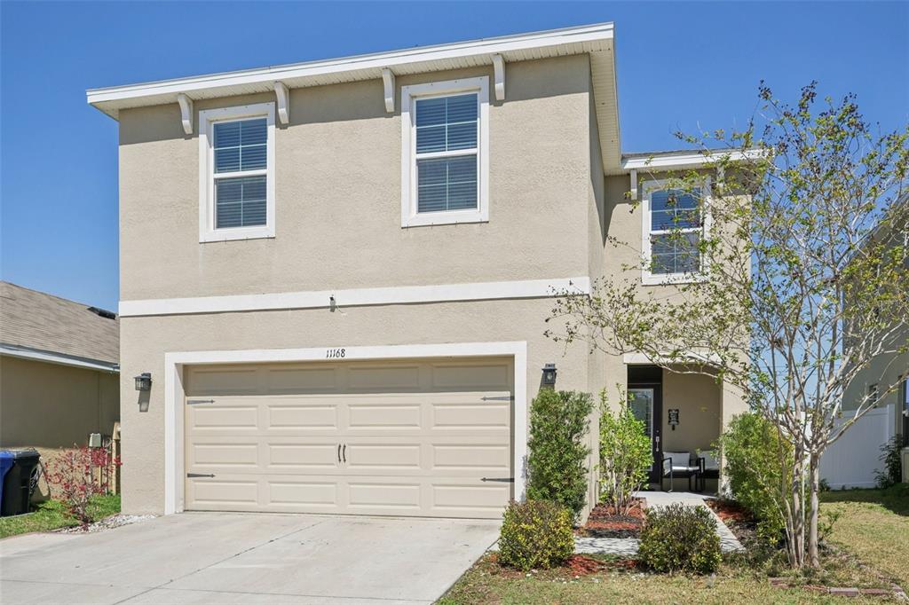 A two-story house with a beige stucco exterior, a two-car garage, and a front entrance — 11168 LELAND GROVES DRIVE, RIVERVIEW, FL