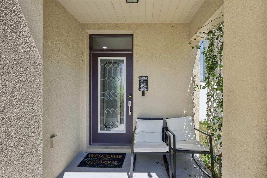 A covered front porch features a purple door, two chairs with white cushions, and a doormat — 11168 LELAND GROVES DRIVE, RIVERVIEW, FL