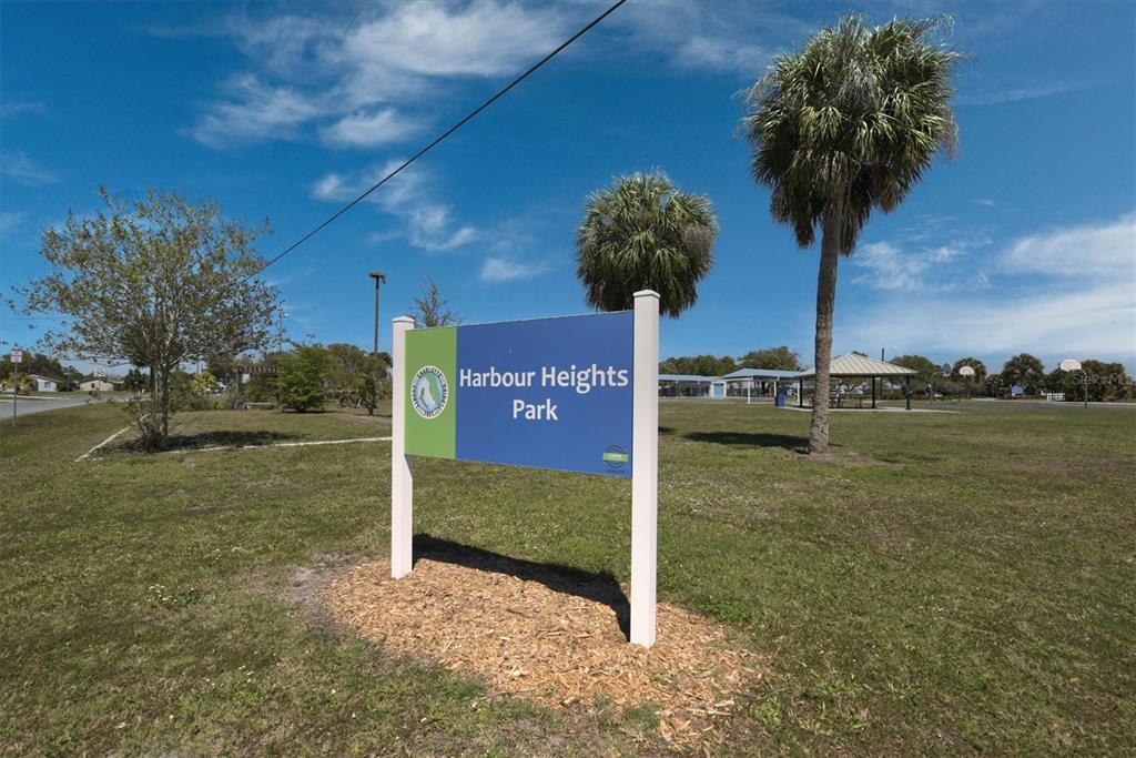 A sign for Harbour Heights Park stands in a grassy field with palm trees nearby — 27119 MONROE STREET, PUNTA GORDA, FL