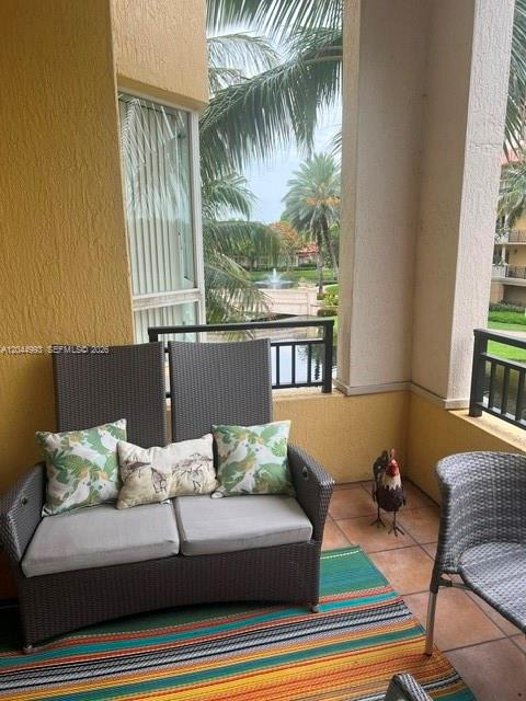 A patio features a wicker loveseat with patterned pillows on a colorful striped rug — 16102 Emerald Estates Dr # 235, Weston FL 33331, WESTON, FL