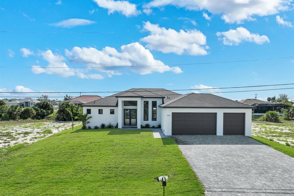 A modern single-story house with a two-car garage and a paved driveway — 1925 NW 34TH PLACE, CAPE CORAL, FL