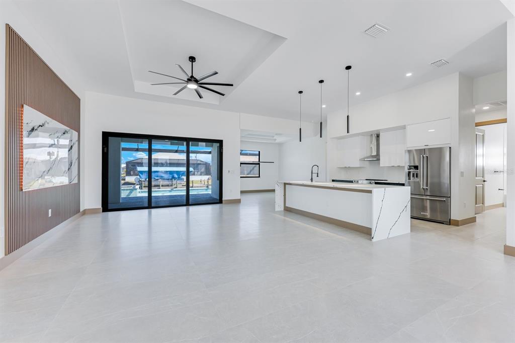A modern open-concept kitchen and living area featuring white cabinetry, a marble island, and sliders — 1925 NW 34TH PLACE, CAPE CORAL, FL